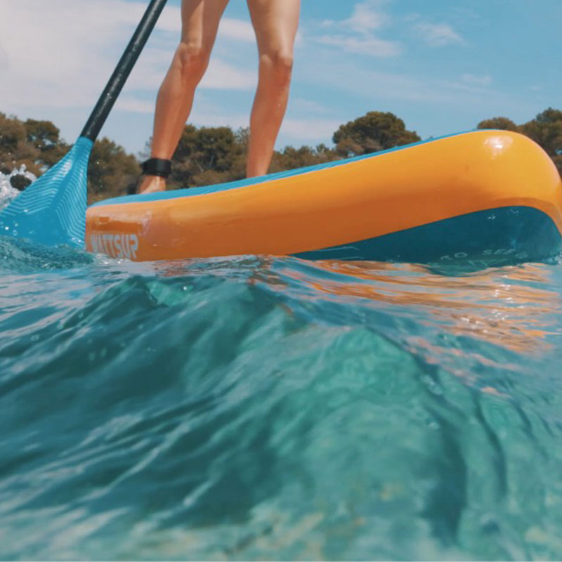 Un stand up paddle avec bordure orange sur une eau claire